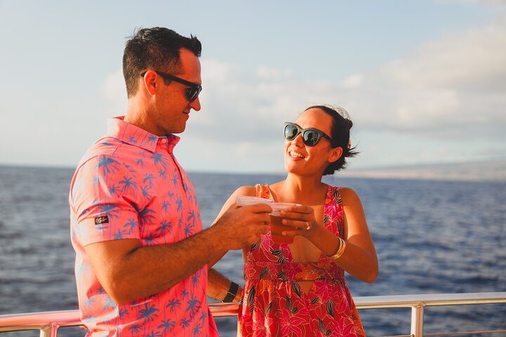 Couple with drinks on deck at sunset